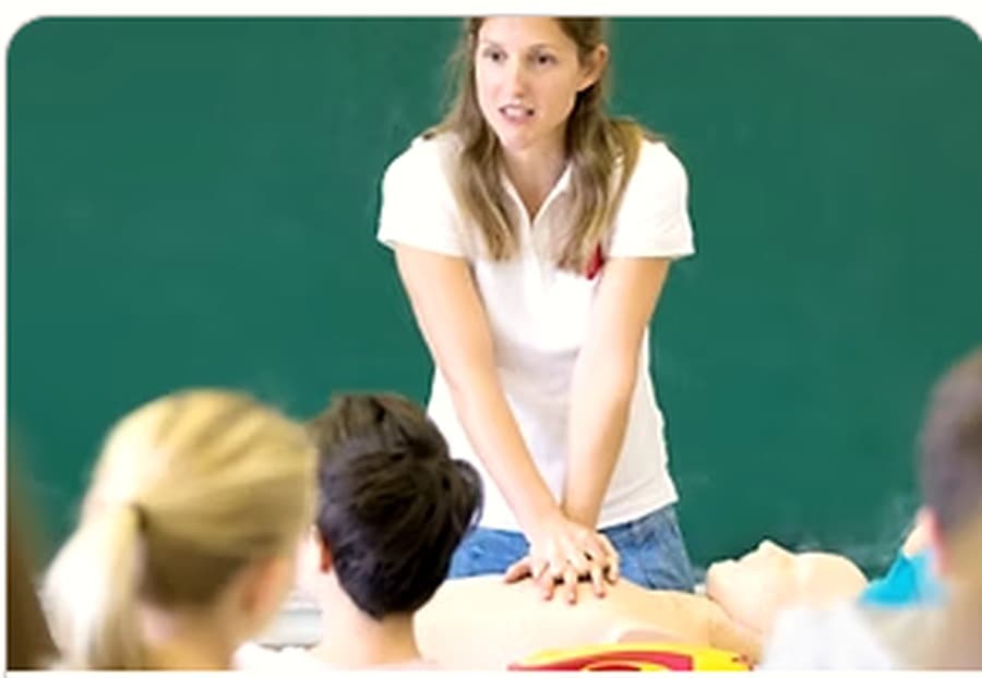 An instructor demonstrating chest compressions on a CPR training manikin.
