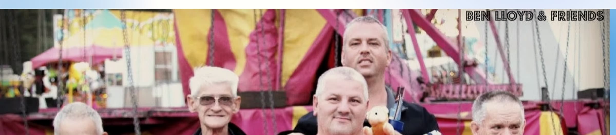 Ben Lloyd and friends together at a local fair, smiling in front of a fairground ride.