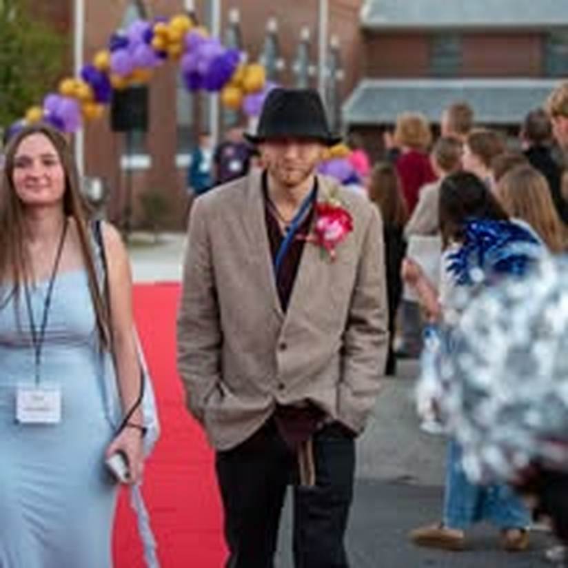A young couple walking the red carpet at a community gala.