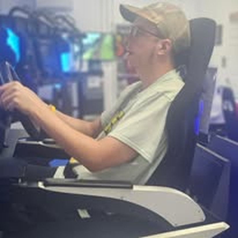 An individual in a wheelchair enjoying a gaming station at the arcade.