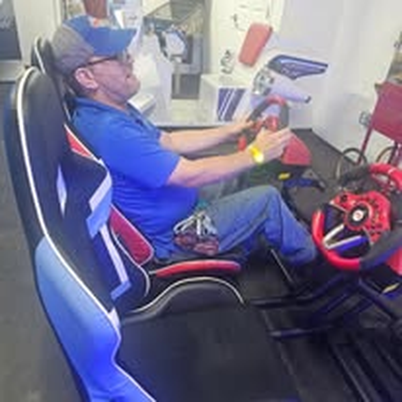 A staff member behind the wheel of an arcade racing simulator.