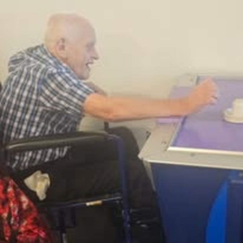 An individual in a wheelchair reaching for a table game.