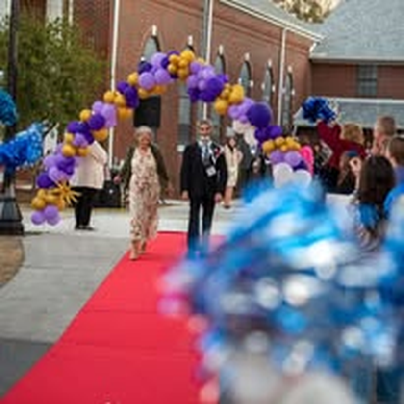 An older couple sharing a joyful walk down the red carpet.