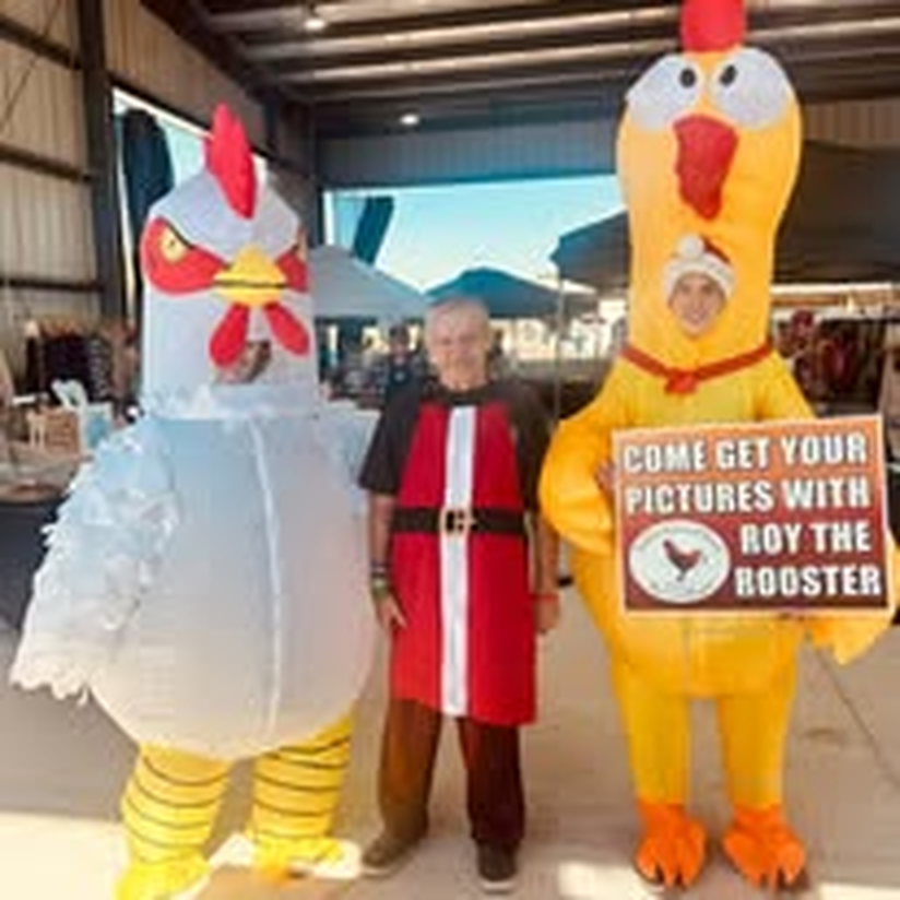 Staff posing with Roy the Rooster and a friend in chicken costumes at a farm event.