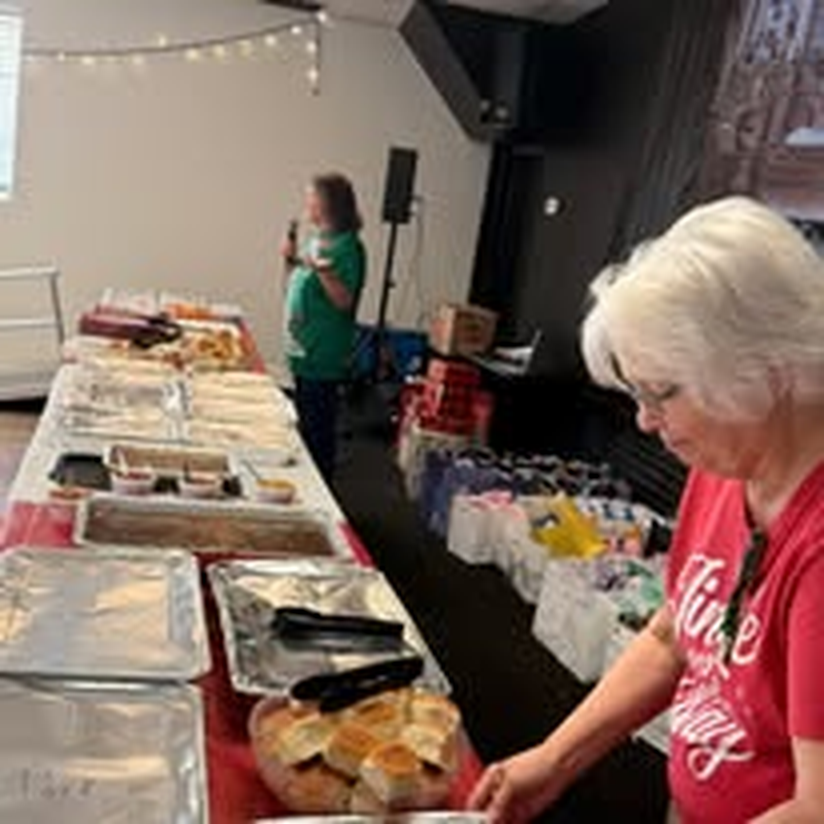 Volunteers serving a community meal along a buffet table.