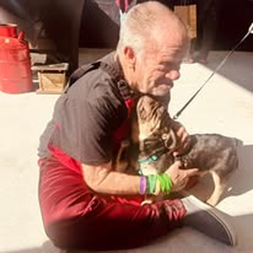 A staff member sharing a gentle moment with a dog outdoors.