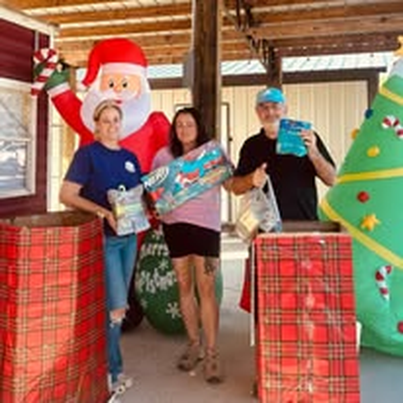 Volunteers handing out holiday gift baskets under a pavilion.